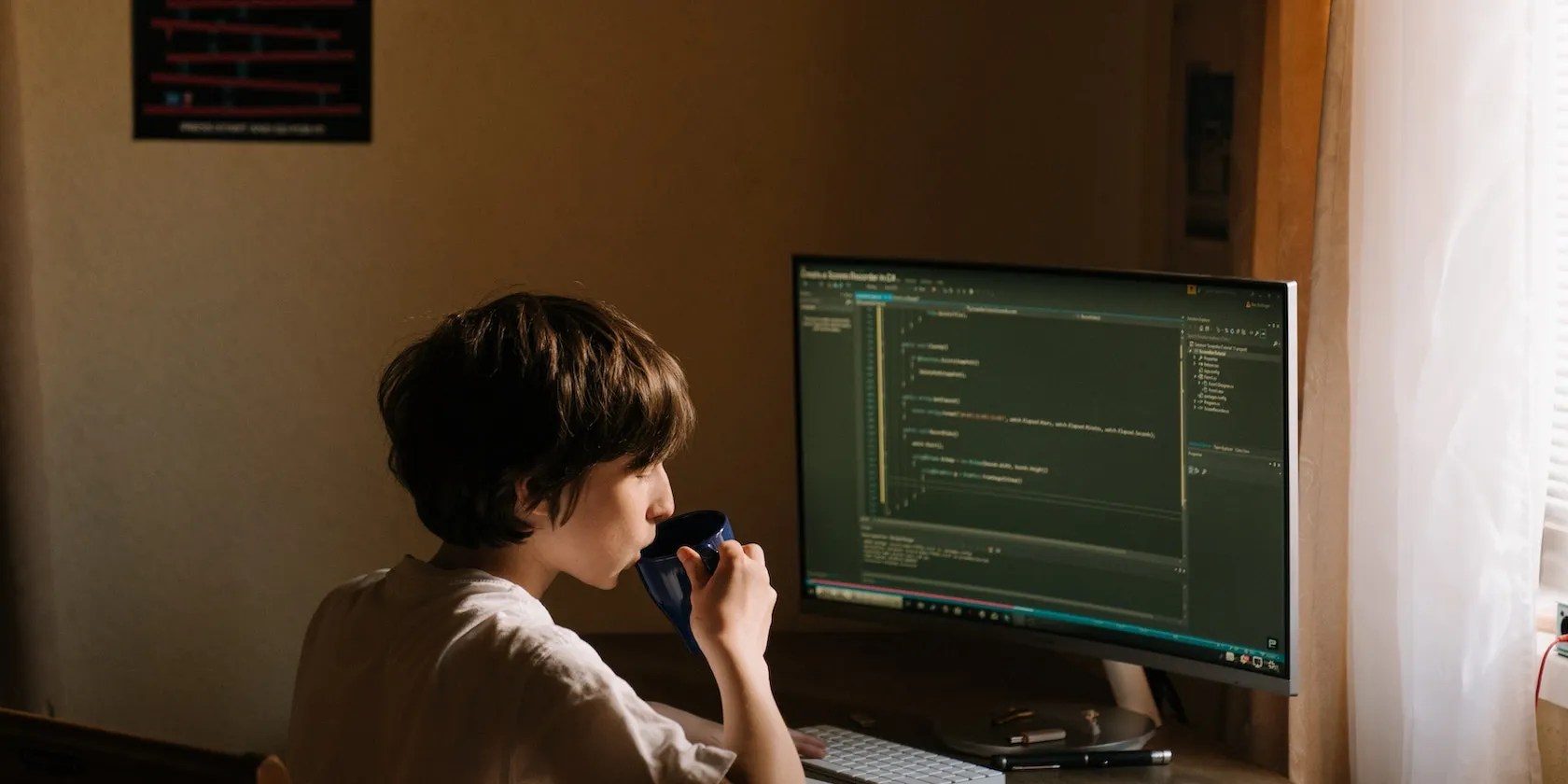 Person in a white T-shirt in-front of a computer displaying code