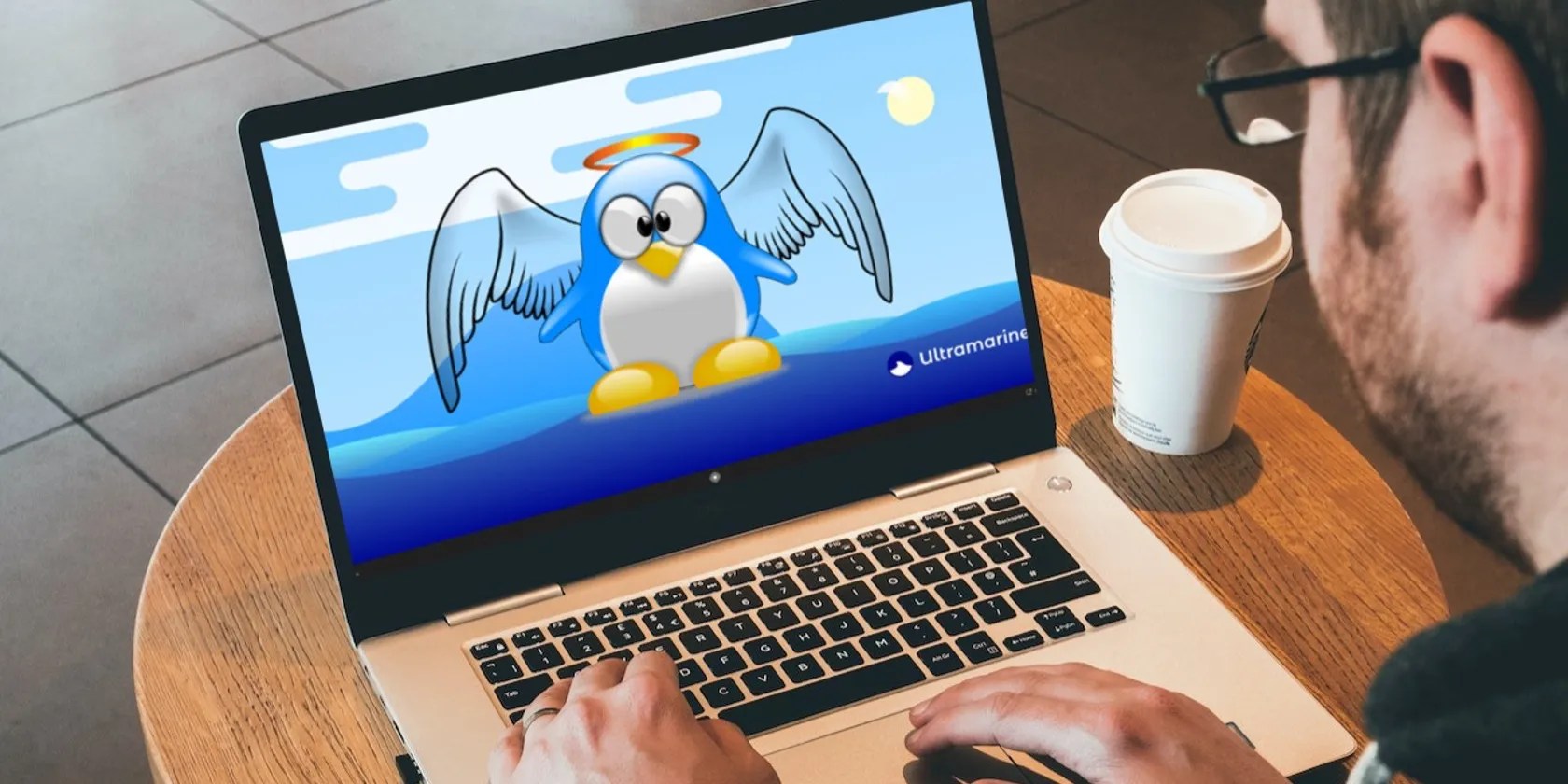 Man with glasses using laptop on the little table in the cafe