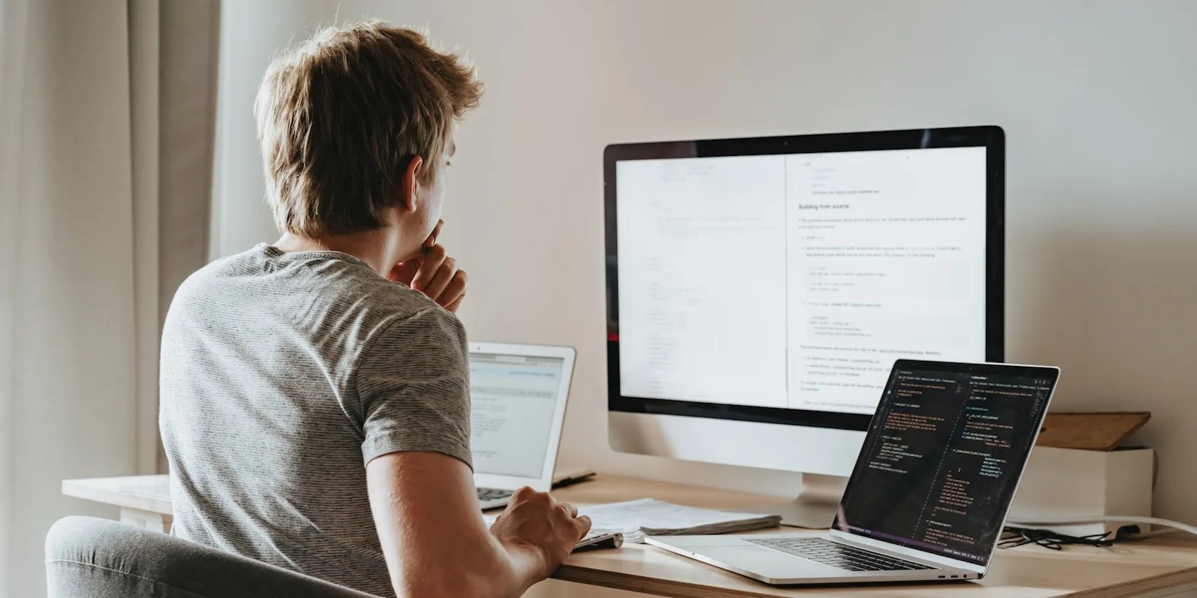A Man Sitting In Front Of Two Computers