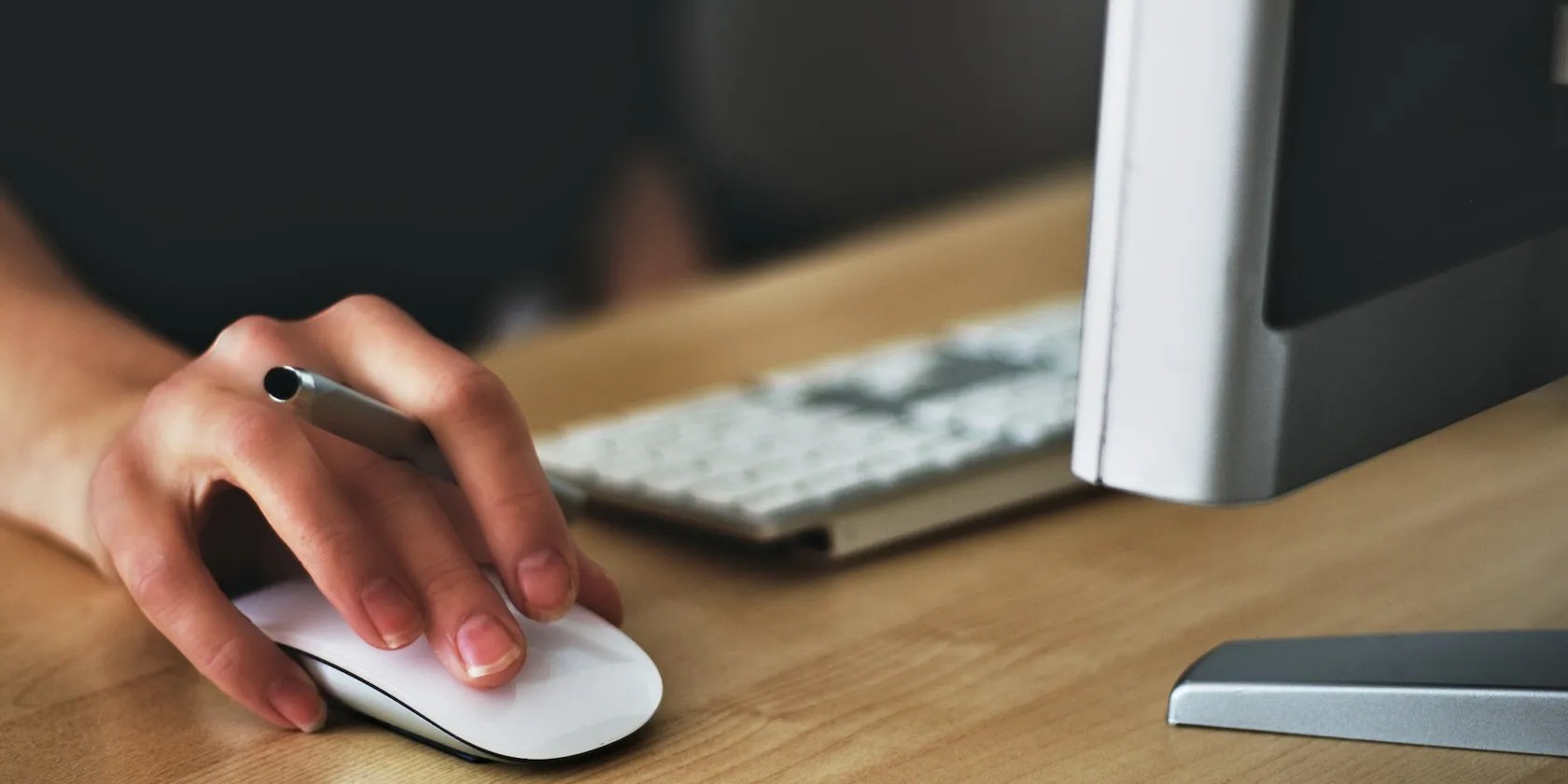 A person holding Apple Magic Mouse and clicking