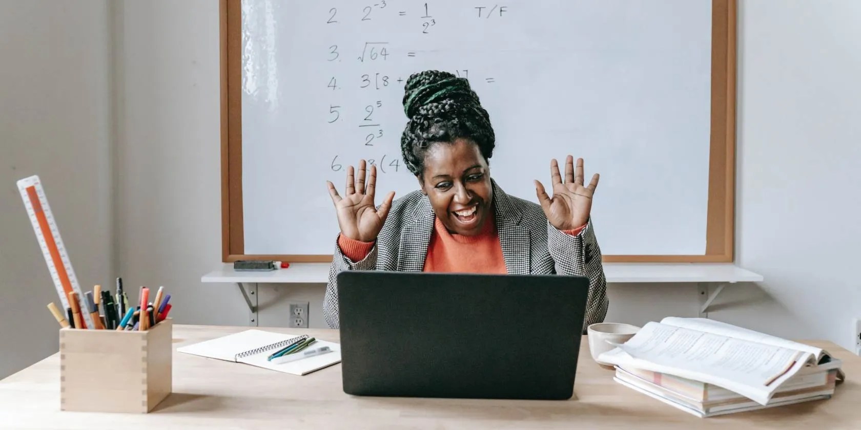 Woman looking at laptop with Whiteboard behind her