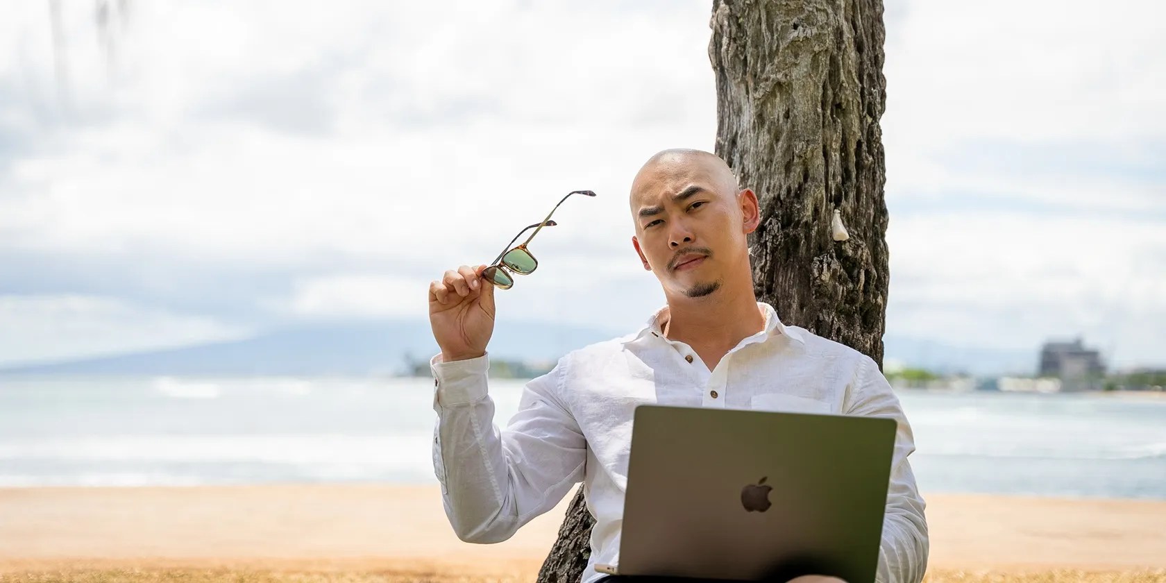 man on a beach with his sunglasses in hand