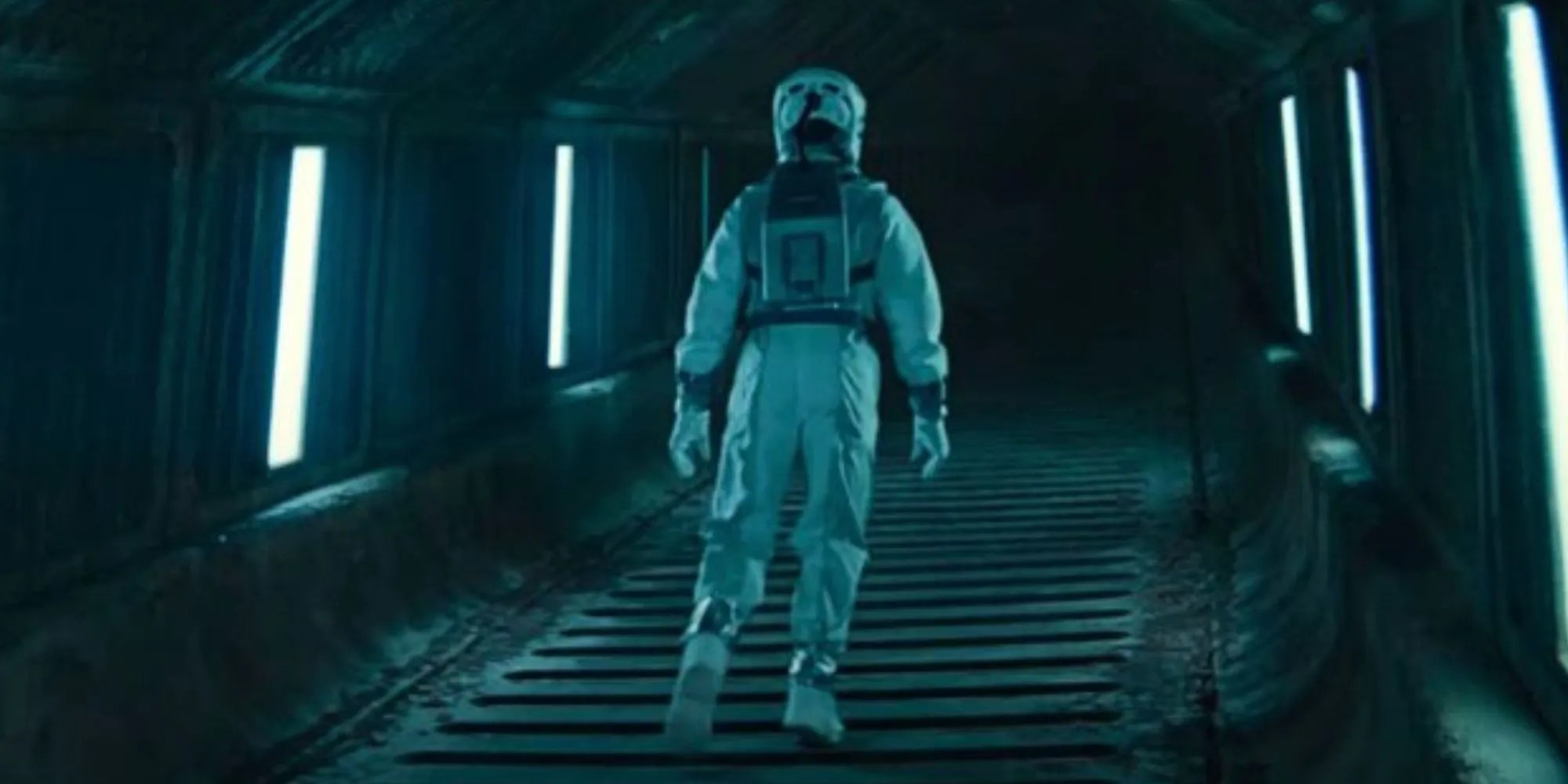 Rebecca Ferguson as Juliette Nichols in an environment suit walking down a passageway in Silo
