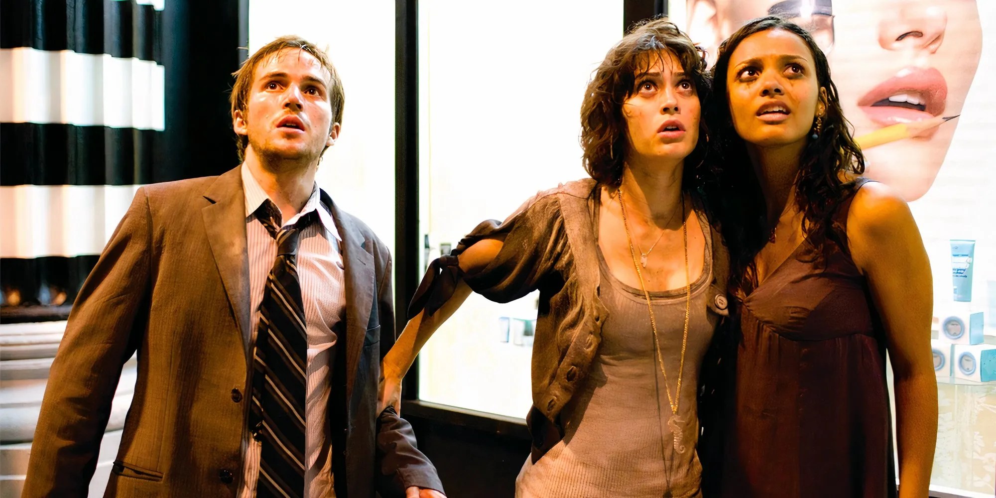 Three characters in Cloverfield look up at something with frightened expressions