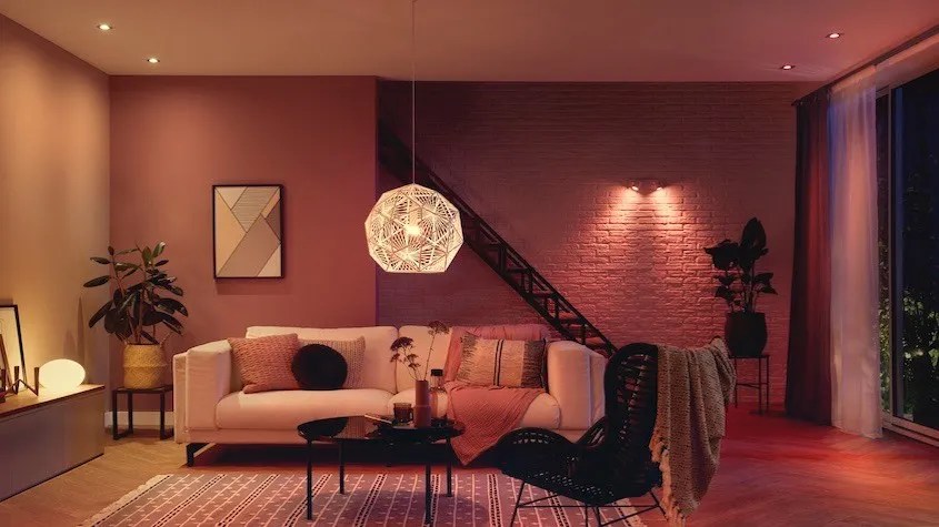 living room with a painted brick wall, sofa, chair, table and soft overhead and accent lighting.