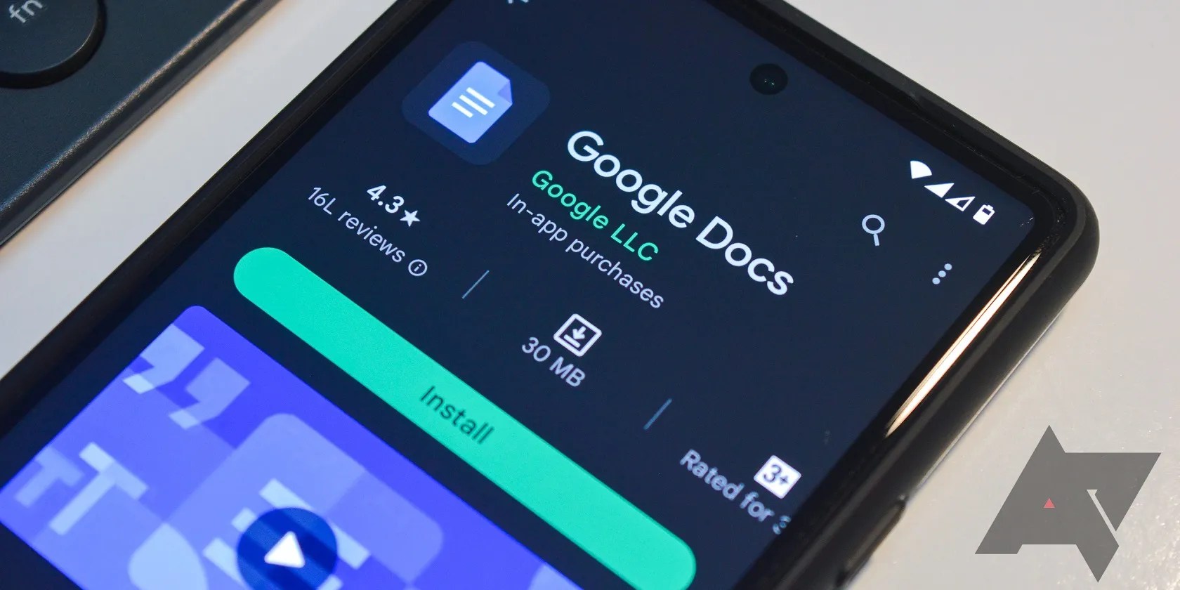 Image shows an Android smartphone laying on a desk, with the phone screen open to the Google Docs download page in the Google Play store.