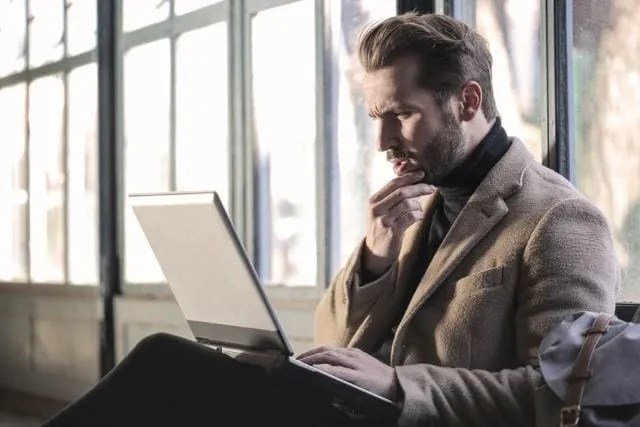 man-wearing-brown-jacket-and-using-grey-laptop