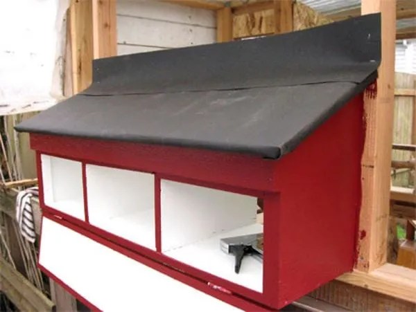 Stylish Nesting Box attached to a wooden house with red and black paint