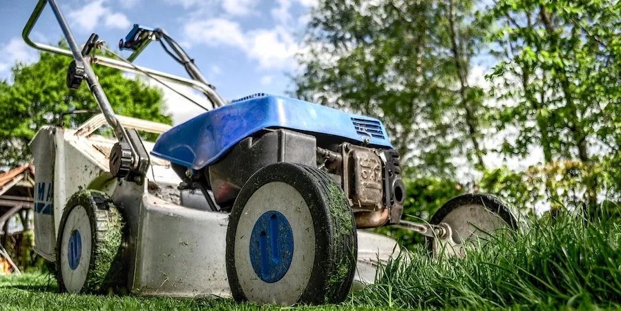 Blue and black lawnmower mowing the lawn