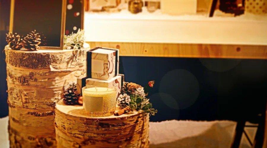 Christmas gifts, decoration and candle on wooden log