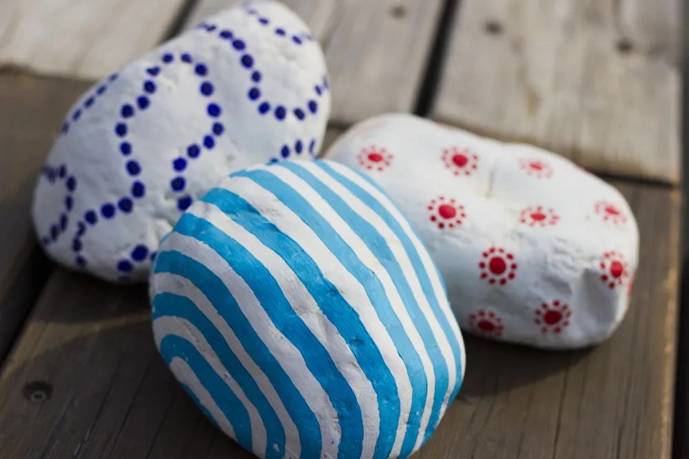 Three decor colored stones on the old wooden floor. Hand-Painted pebbles. Art decor.