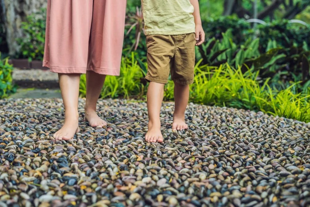 Mother and son Walking On A Textured Cobble Pavement, Reflexology. Pebble stones on the pavement for foot reflexology.