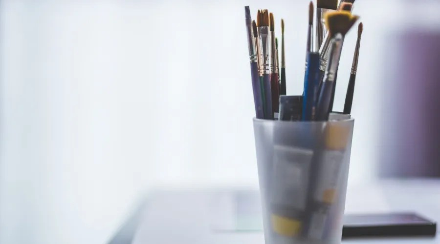 an assortment of paintbrushes in a cup on a table