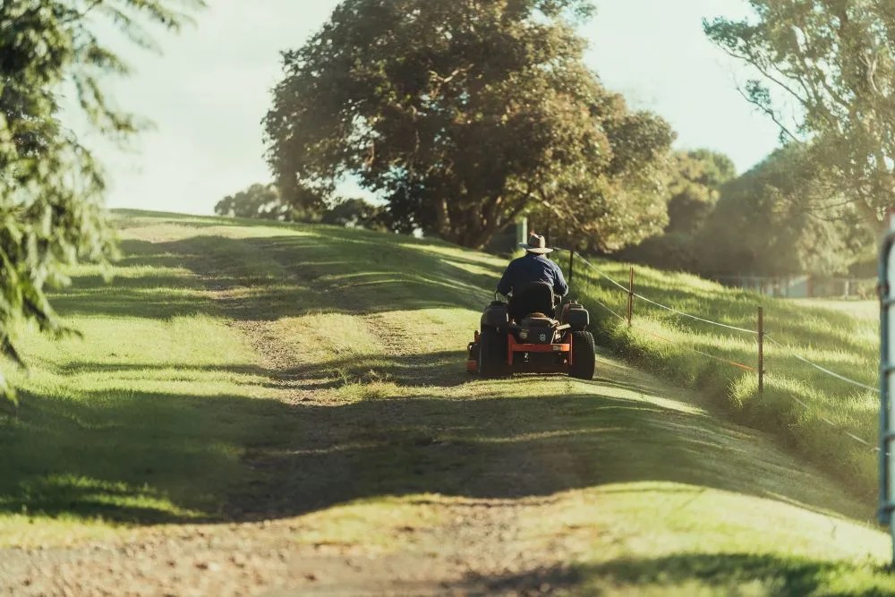 A man mows a large lawn on a riding lawn mower