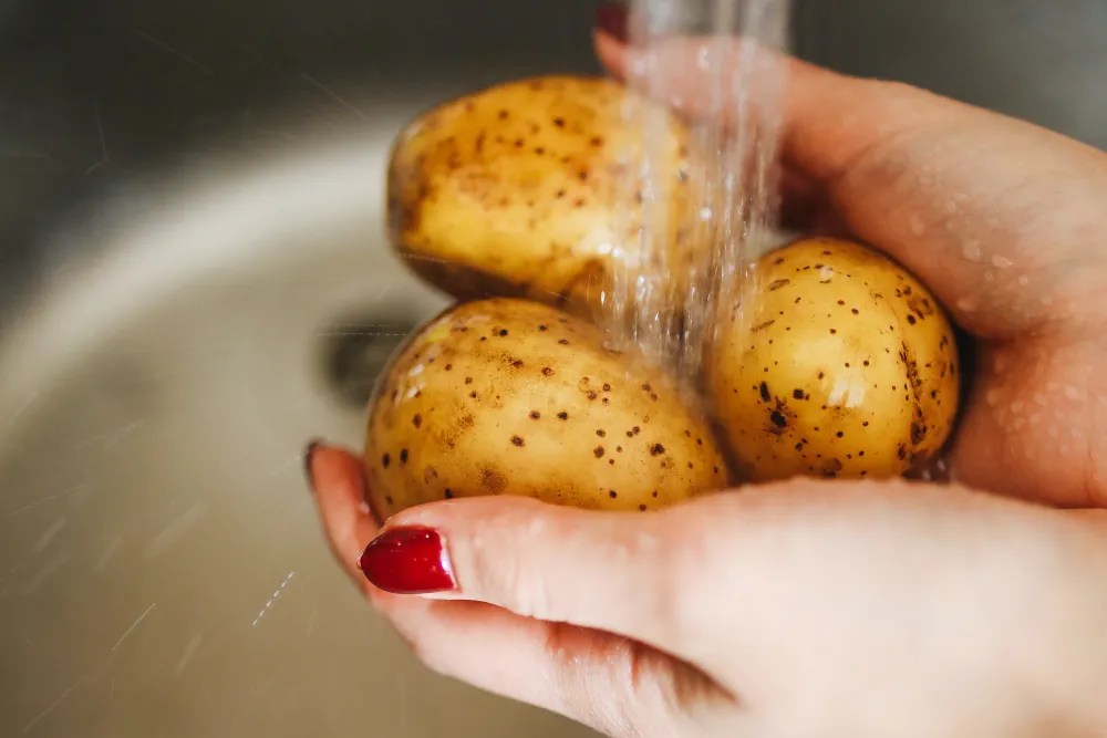 Person washing potatoes in the sink