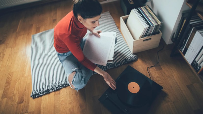Young audiophile playing vinyl record on turntable in her home