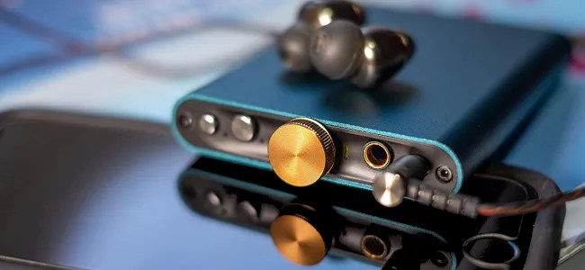 An aqua marine portable DAC resting on top of a smartphone.