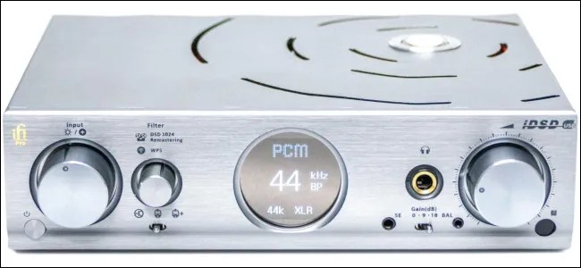 An external DAC with silver chassis and circular LCD display.