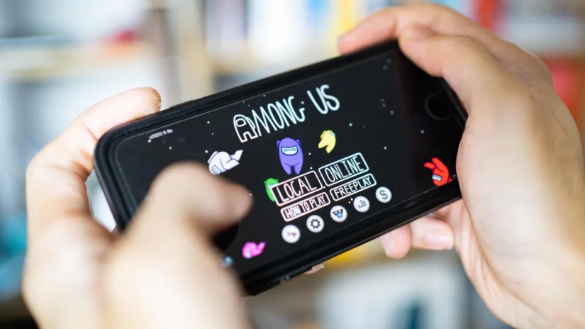 Closeup of hands playing the game &ldquo;Among Us&rdquo; on a smartphone