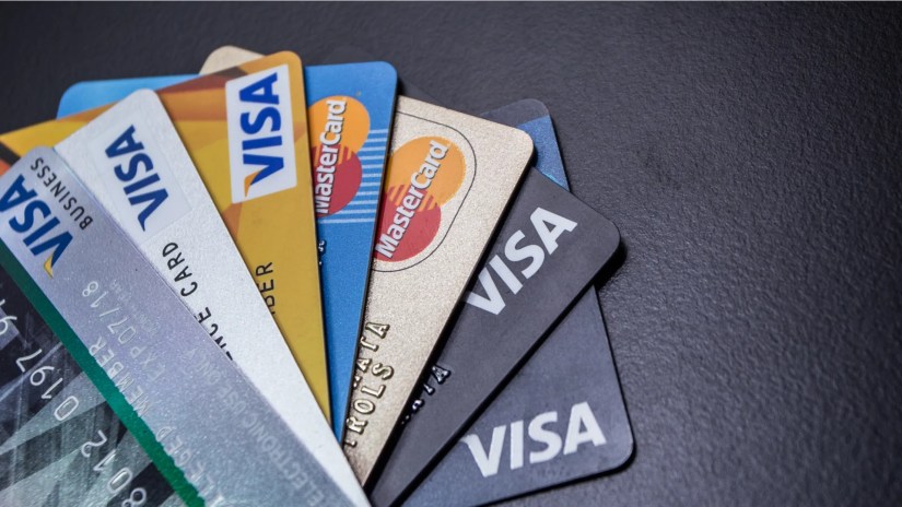 A pile of credit cards from various issuers sitting on a table.
