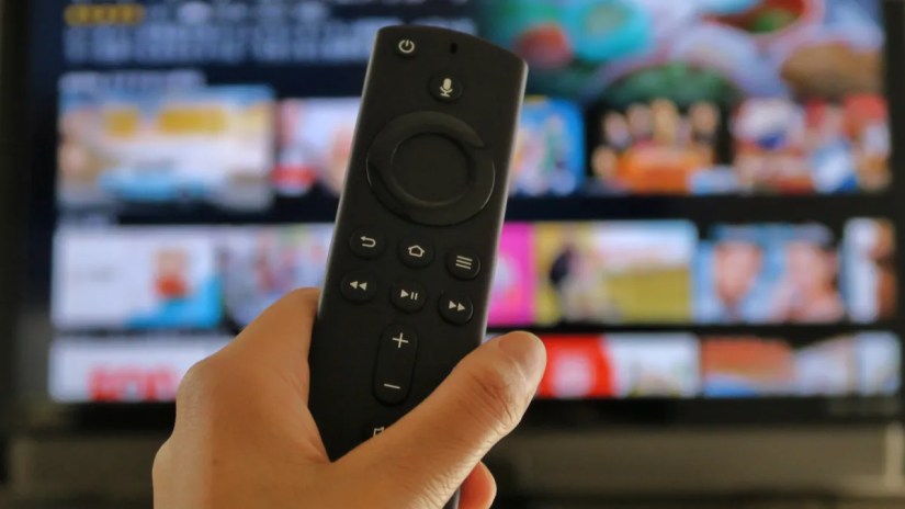 Closeup of an Amazon Fire TV Stick remote in front of a television screen.