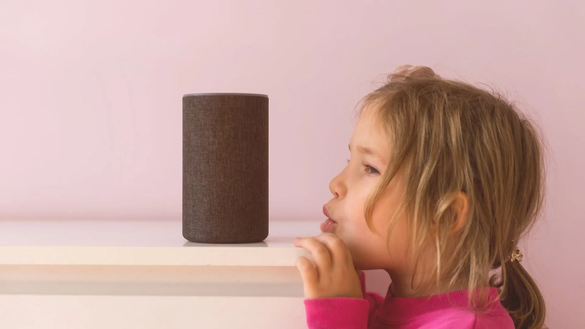 A small girl speaking to an Amazon Echo.