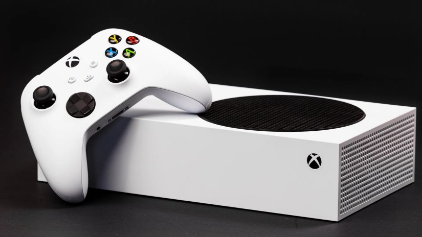 An Xbox Series S placed horizontally with an Xbox Series controller resting on it.