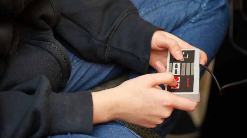A person using a Nintendo Entertainment System controller.