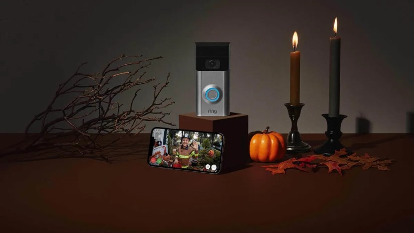 A ring doorbell and smartphone, surrounded by Halloween decor.
