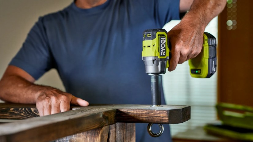 Man using a Ryobi impact wrench in the garage.