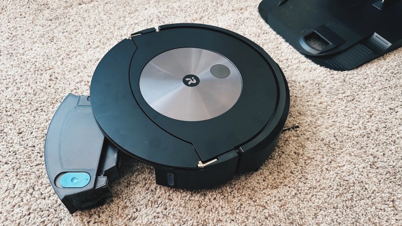 The water tank being removed from a robot vacuum.