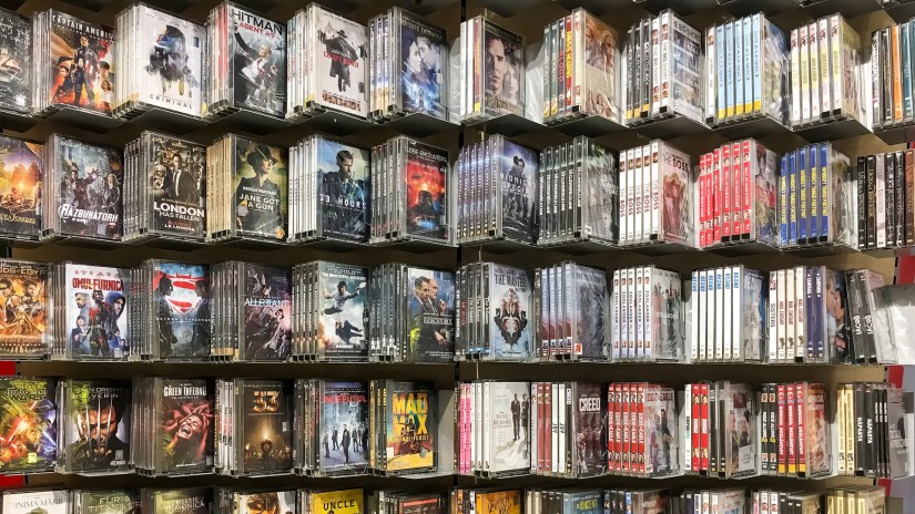 Dozens of physical movie copies on a store shelf.