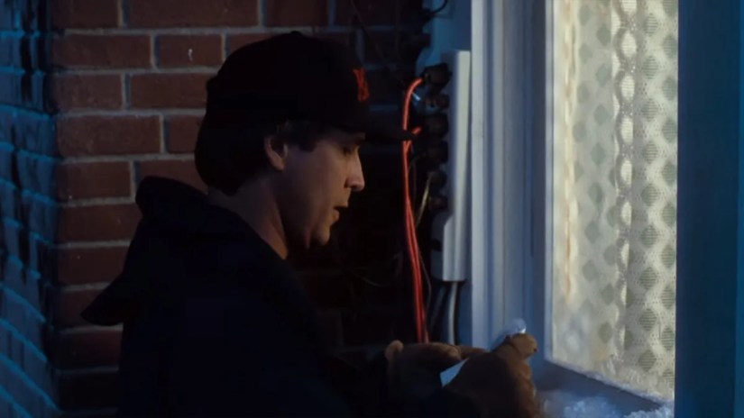 A man checking his Christmas light plans next to an overloaded power strip.