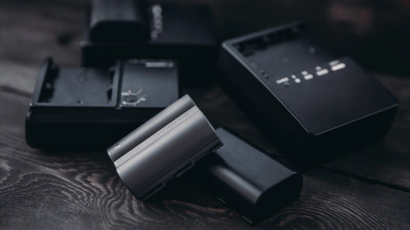 A pile of DSLR camera batteries and chargers.