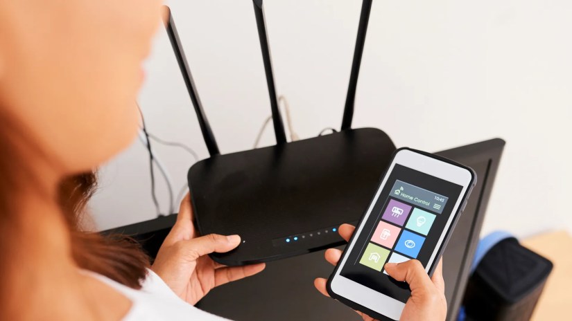 Hands of woman connecting smart home application on her phone to Wi-Fi router.
