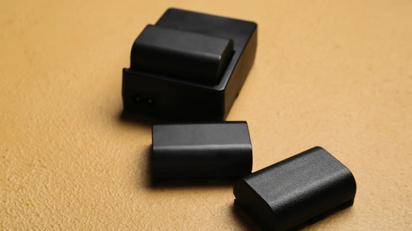 A pile of camera batteries on a table.