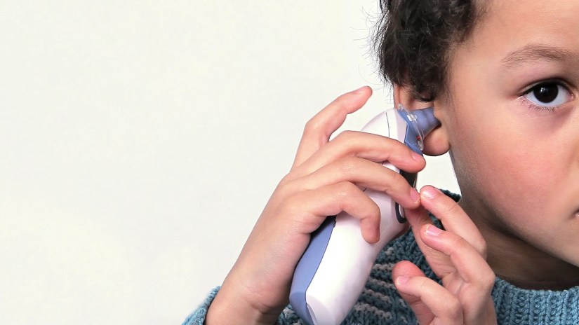 A child using an ear thermometer on themselves.