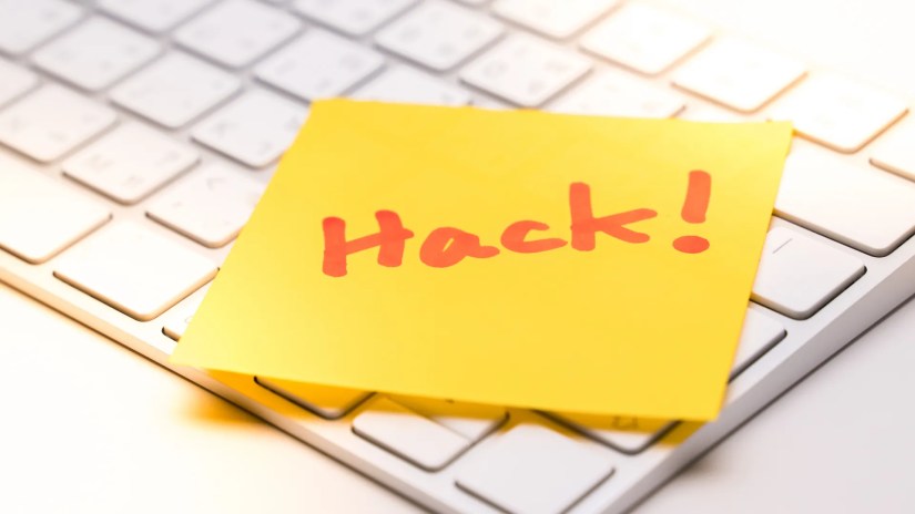 &quot;Hack&quot; written on a sticky note on a computer keyboard.