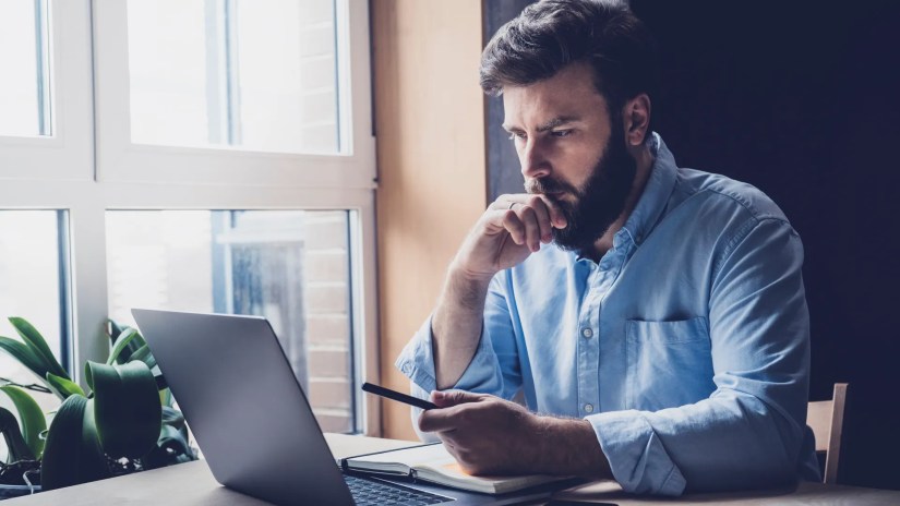 Man thinking and looking at a laptop.