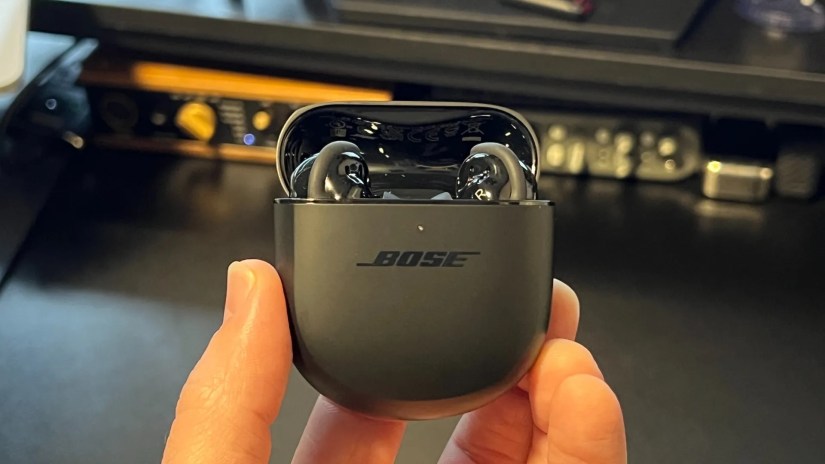 Bose QuietComfort Earbuds in open black case above black desk
