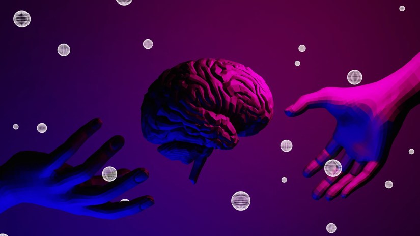 Two hands reach towards a human brain from either side of the frame. What looks like bubbles dot the image.