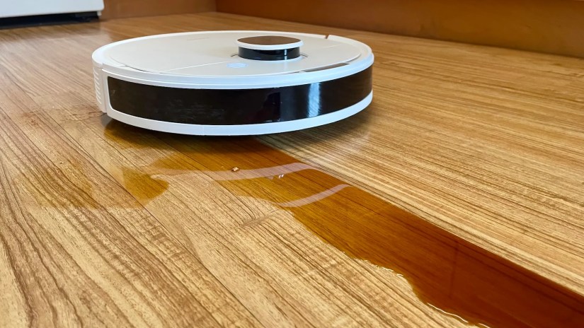 The Ecovacs Deebot N10 Plus cleaning coffee off a kitchen floor.
