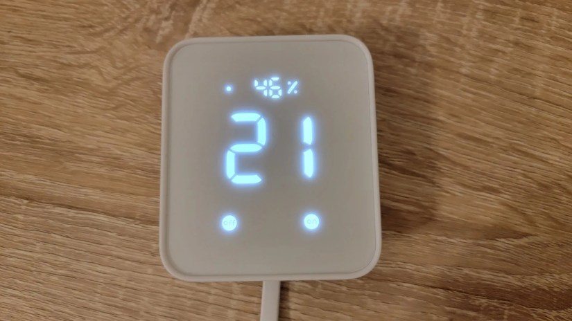SwitchBot Hub 2 on wood table showing temperature and humidity.