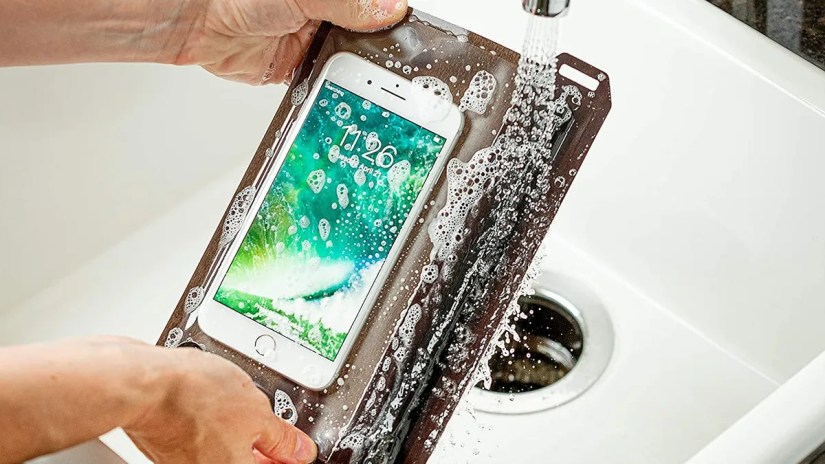 Person washing ite Ize Runoff Waterproof Travel Pouch with phone in it