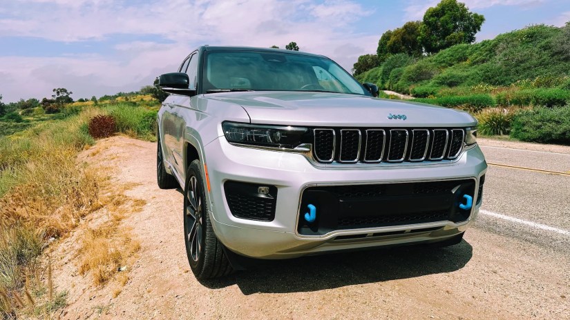 A front view of the Jeep Grand Cherokee on a dirt clearing next to a road