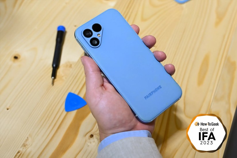 A person holding a Fairphone over a work bench.