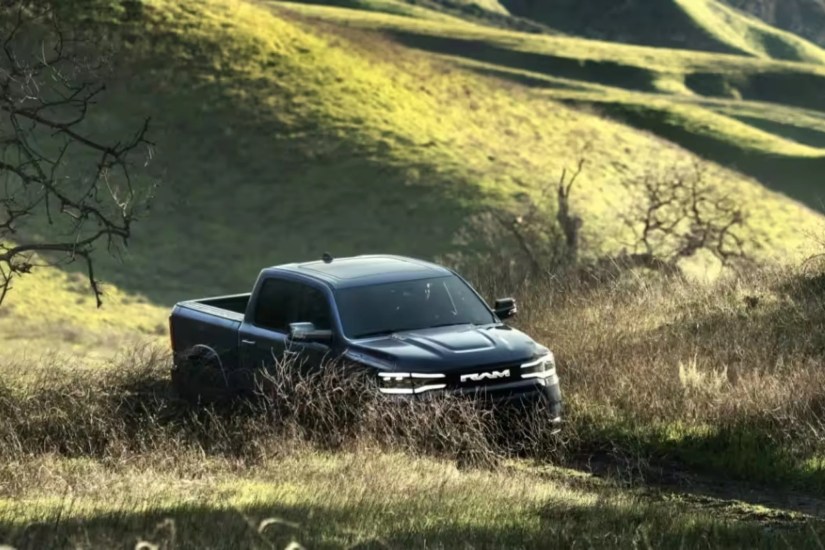 Ram 1500 REV electric truck driving on a dirt road in the mountains.