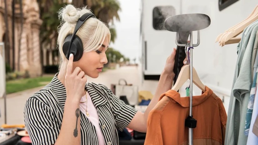 Young woman wearing Bose Headphones 700 while steaming clothes.