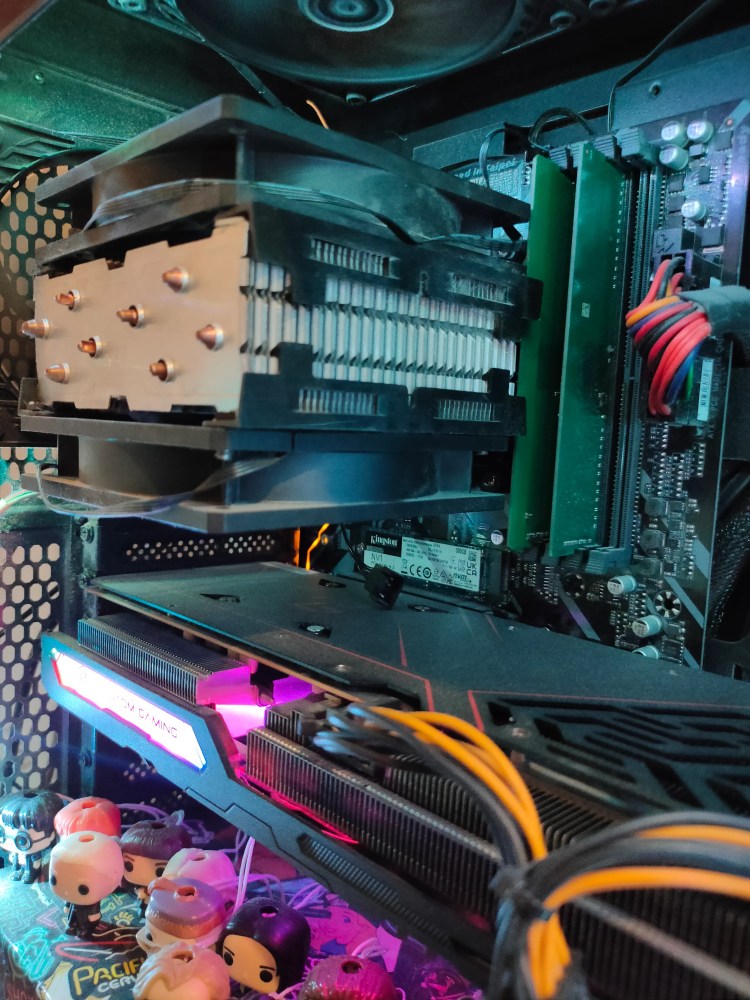 Image of an air CPU cooler with two fans inside a computer with a modern gaming graphics card beneath it.