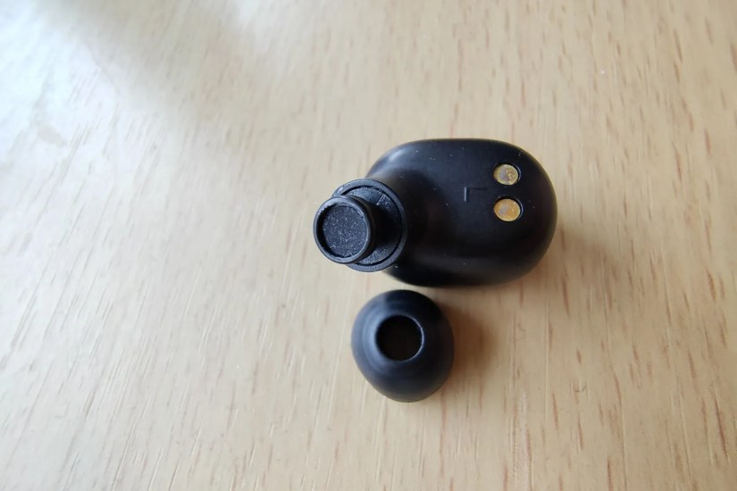 A close-up photo of black wireless earbuds with the silicon tip removed.